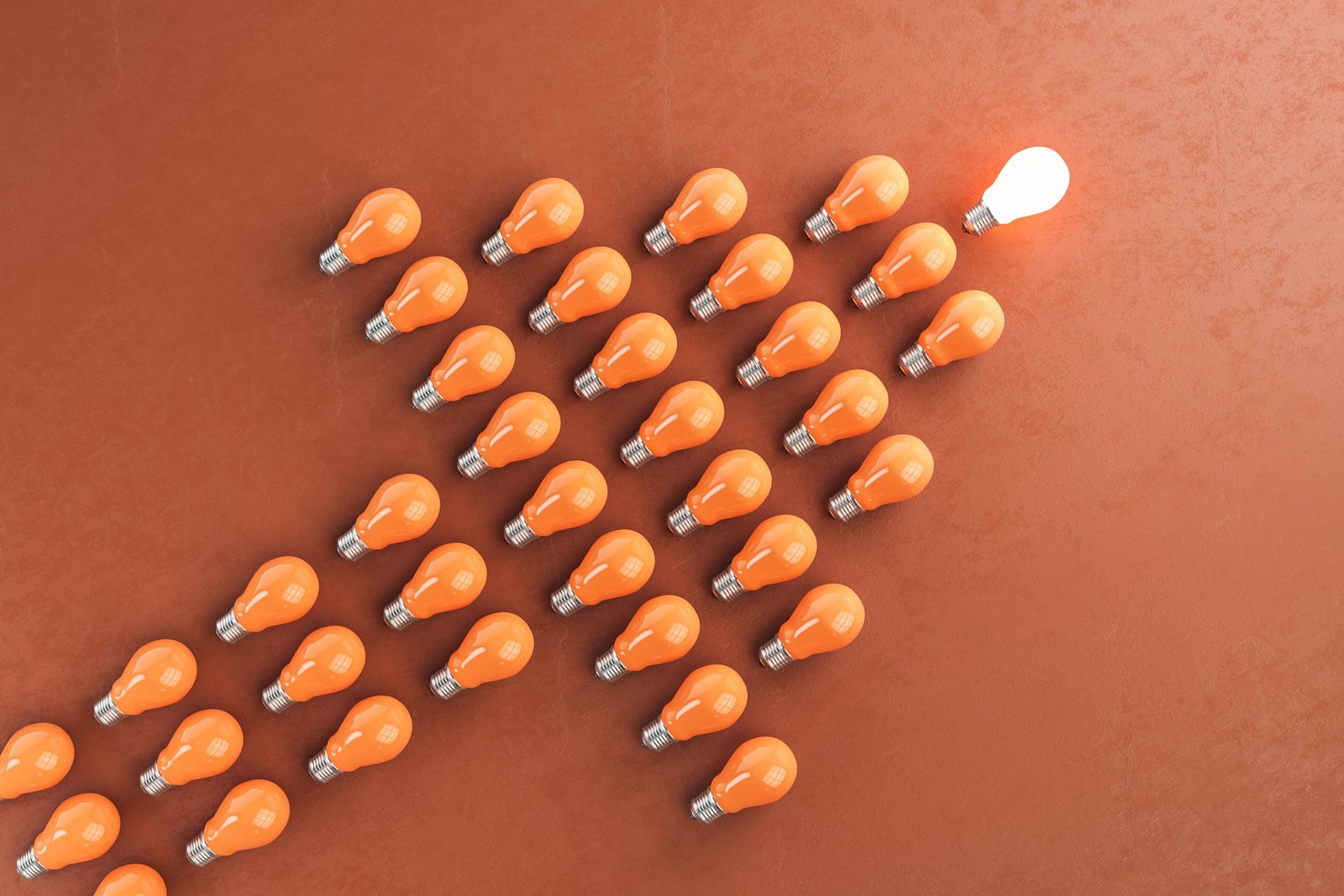 Glowing light bulb and many light bulb in form of an arrow on orange background. Idea and leadership concept. 3D Rendering