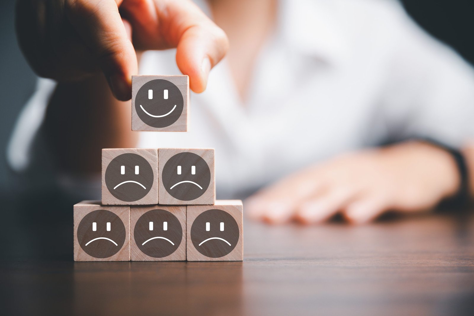 Customer service evaluation and satisfaction survey concepts. The client's hand picked the happy face smile face icon and five star symbol on wooden cube on table