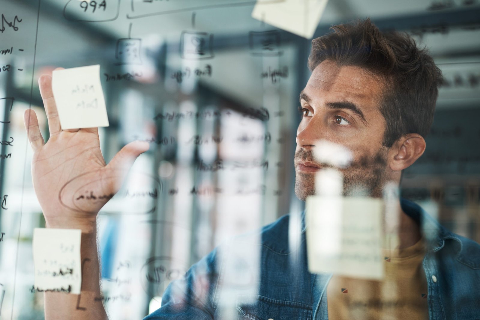 Planning, man and glass with solution in startup for brainstorming, information or organizing project goal. Entrepreneur, sticky note and ideas on paper for reminder, timeline and agenda schedule.