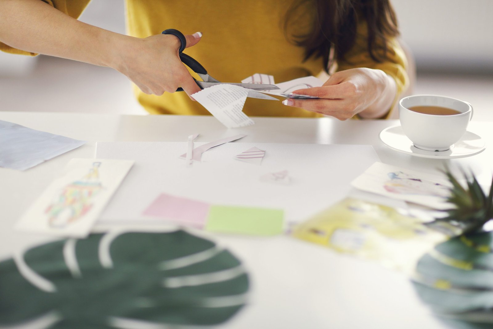 Young brunette woman creating her Feng Shui wish map using scissors